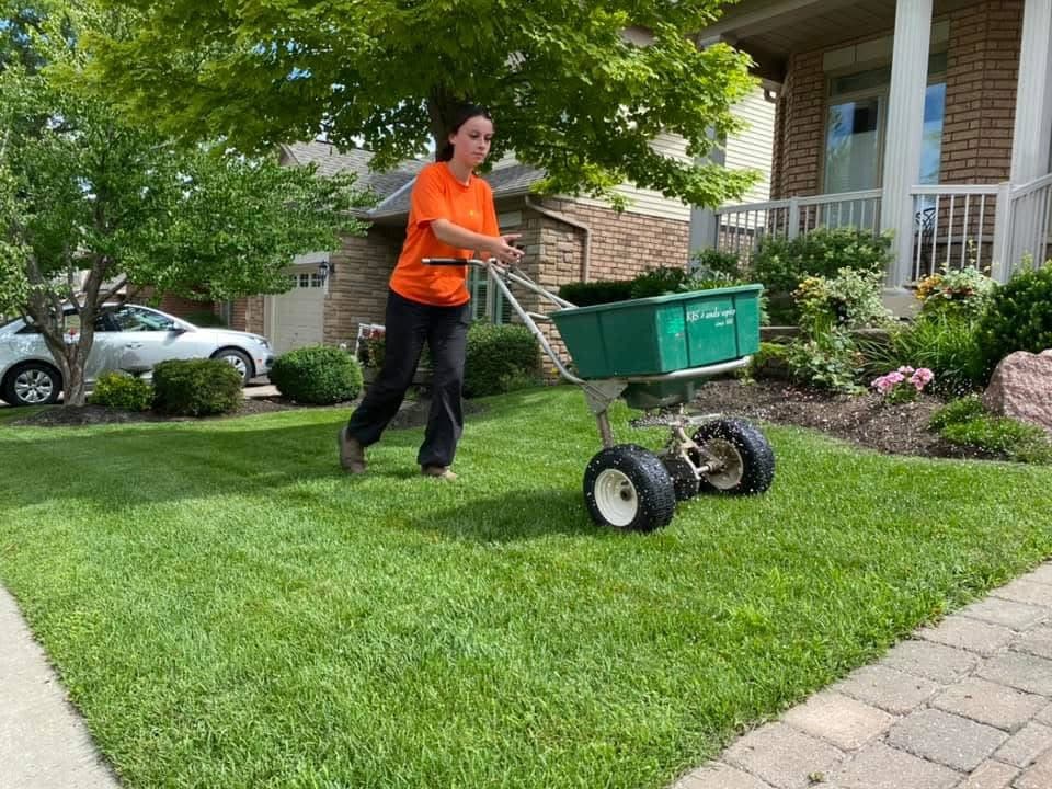KJS crew member applying fertilizer on residential front lawn