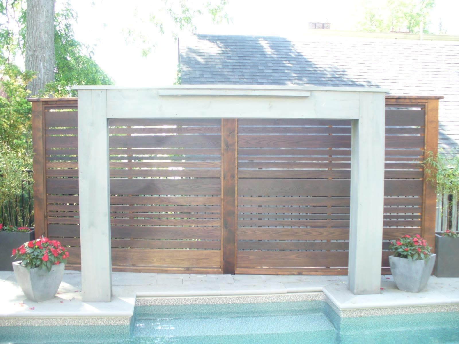 Custom horizontal-slat wooden privacy screen alongside pool