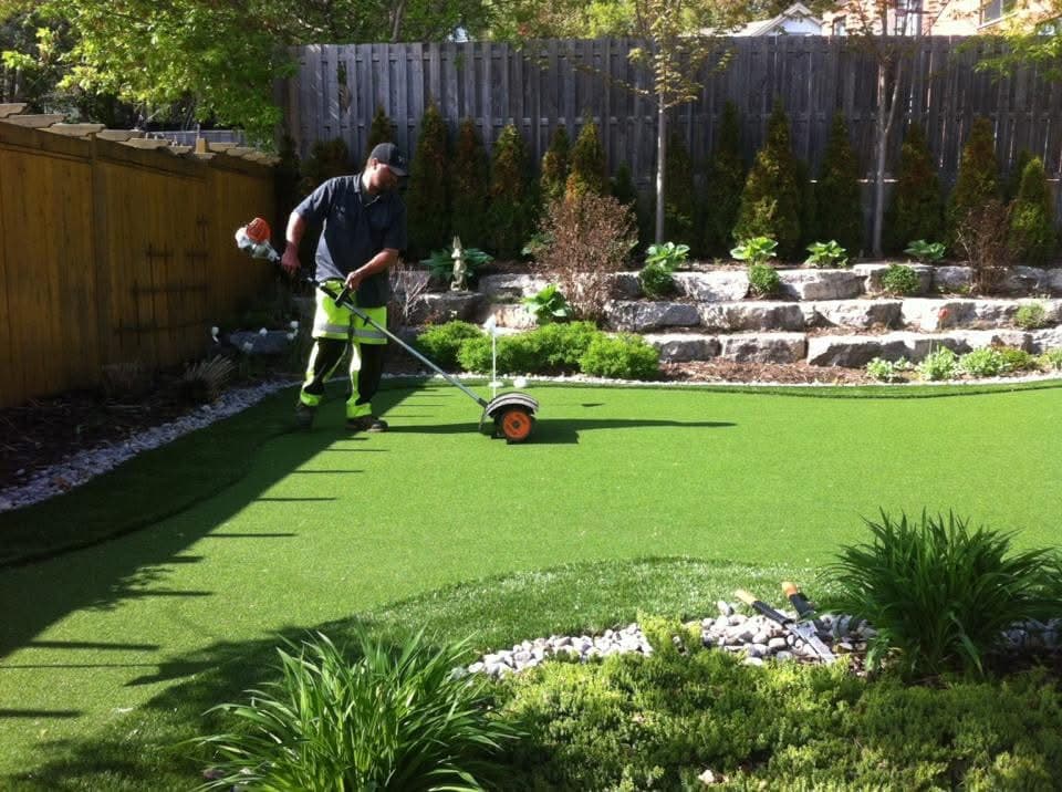 Crew maintaining artificial putting green and surrounding garden beds