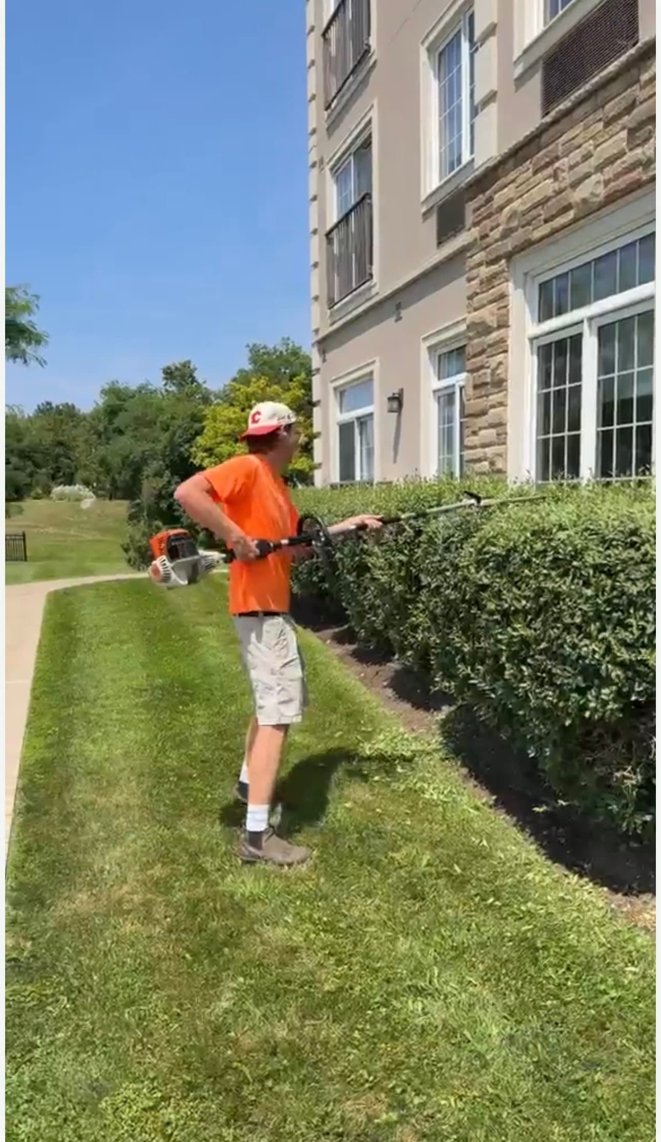 KJS crew member trimming hedges at retirement community building